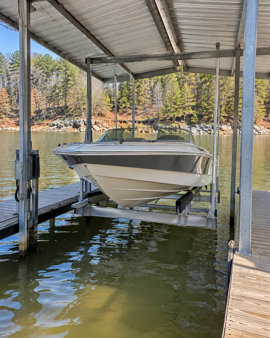 A motorboat held clear of the water on a cradle lift under a dock roof